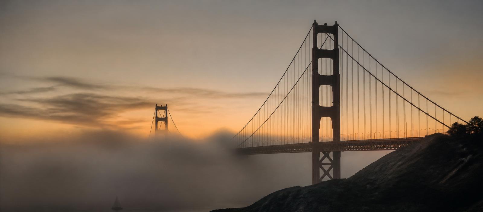 Golden Gate Bridge in fog at dusk.